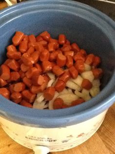 chopped carrots and onions in a blue bowl on a wooden counter top next to an electric blender