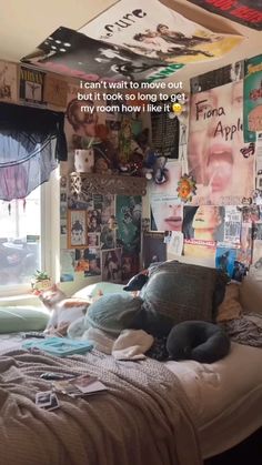 an unmade bed in a bedroom with posters on the wall and pictures above it