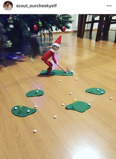 an elf is playing golf on the floor in front of christmas trees and balls that are scattered around