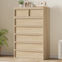 a wooden dresser with drawers in a living room next to a chair and potted plant