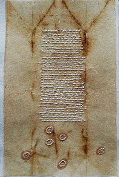 a piece of brown paper with white thread on it and holes in the middle that have been stitched together