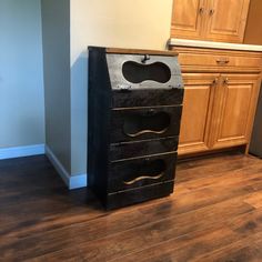 an empty kitchen with wooden floors and cabinets in the background, including a black file cabinet