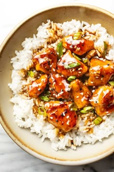 a white bowl filled with rice and tofu on top of a marble countertop