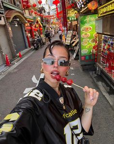 a woman wearing sunglasses and eating food on a stick