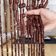 a hand is holding beads that are hanging from the ceiling