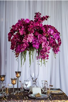 a vase filled with purple flowers sitting on top of a table next to two candles