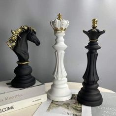 three black and white chess pieces sitting on top of each other next to some books