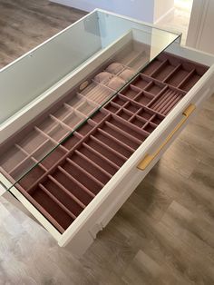 an open drawer with many compartments on the top and bottom, sitting on a hard wood floor