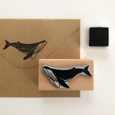 a rubber stamp with a whale on it next to a piece of paper and a rubber seal