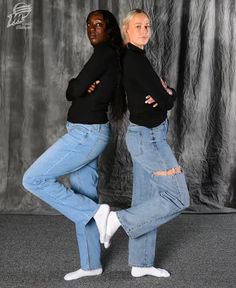 two women in black sweaters and jeans posing for the camera