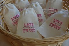 four small bags with love is sweet printed on them in a wicker basket,