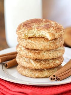 cinnamon sugar cookies stacked on top of each other with cinnamon sticks next to them and a glass of milk in the background