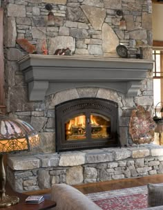 a stone fireplace in a living room with two lamps on either side of the fire place