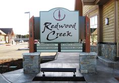 a sign for redwood creek creek is shown in front of a building with stone pillars