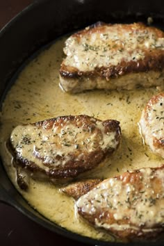 pork chops are cooking in a skillet with creamy lemon sauce on top