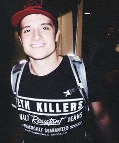 a young man wearing a red hat and black t - shirt smiles at the camera