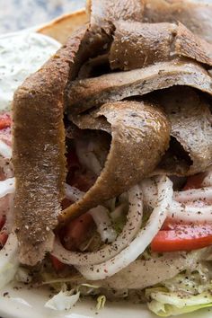 a sandwich with meat, onions and tomatoes on it