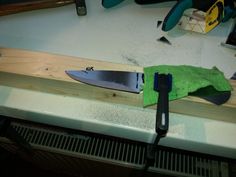 a knife is laying on top of a piece of wood