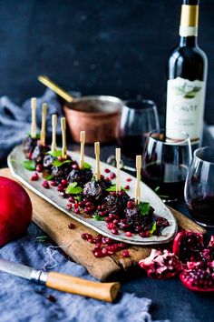 an appetizer is served on a platter with wine and pomegranates