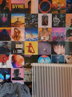 a wall covered in posters and pictures next to a radiator with a blanket on it