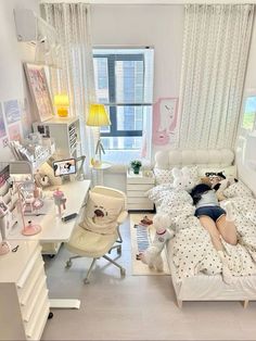 a woman laying on her bed in the middle of a room with white furniture and decor