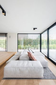 a large white couch sitting on top of a wooden floor next to a window covered in blinds