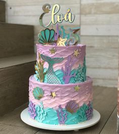 a multi - tiered cake decorated with mermaid decorations and under the sea themed icing