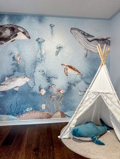 a child's room with a teepee tent and sea animals on the wall