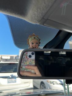 a doll is taking a selfie in the rearview mirror