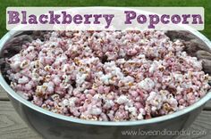 a bowl filled with pink and white popcorn on top of a wooden table next to grass