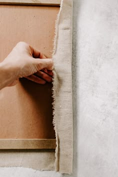 a person's hand is holding the edge of a piece of fabric that has been torn off