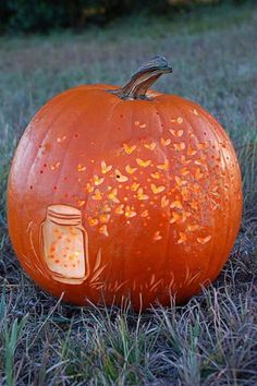 a carved pumpkin sitting in the grass with a mason jar on it's face