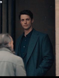 a man standing in front of a door talking to another man who is looking at him