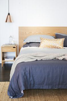 a bed with blue sheets and pillows on top of it next to a night stand