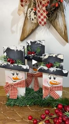 four snowman gift bags sitting on top of a wooden table next to christmas decorations