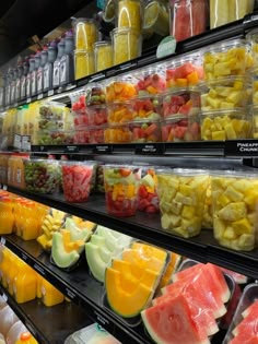 many different types of fruit are on display in a store aisle, including melons and watermelon