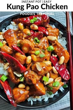 a black plate topped with chicken and rice next to chopsticks on a table