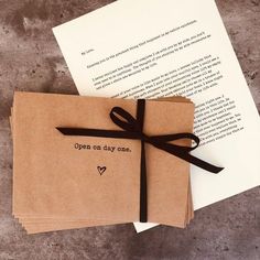 an open book with a ribbon tied around it on top of a piece of paper