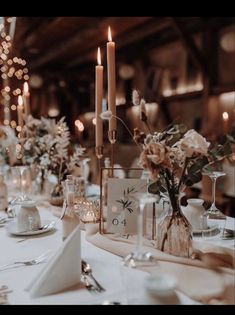 the table is set with candles and flowers in vases, plates and napkins