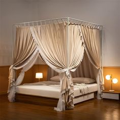 a canopy bed with drapes and pillows on the sides, in a bedroom setting