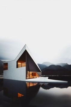 a white house sitting on top of a body of water next to a mountain range