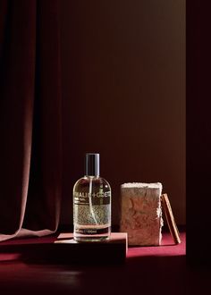 a bottle of liquid sitting next to a piece of bread on a red table cloth