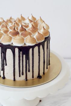 a cake with white frosting and chocolate drizzled on top sitting on a plate