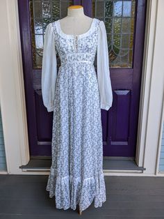 "Beautiful 1970s Gunne Sax dress in a cotton voile print of tiny purple rosebuds with green leaves and tendrils on a white background. The bodice laces up corset style, and it's trimmed in white lace with satin ribbons. The long full sleeves are in white voile dotted Swiss with lace trim on the cuff ends. The skirt is very full, and the dress is in excellent condition. It has a lovely, delicate ethereal fairy vibe. It's a little small across the back for my size 8 dress form, so it's just pinned 1800s Clothes, Tavern Wench, Cottage Clothing, Grandma Dress, Fairy Vibe, 70s Prairie Dress, 80s Inspired Outfits, 70s Prairie, Ethereal Fairy