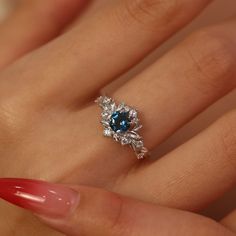 a woman's hand with a blue and white diamond ring on her left hand