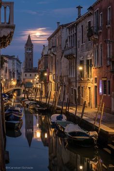 boats are parked along the side of a canal at night