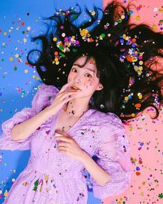 a woman in a purple dress surrounded by confetti and sprinkles