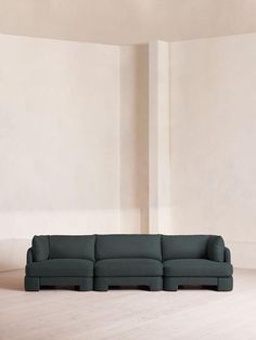 a living room with a sectional couch in the middle and a white wall behind it