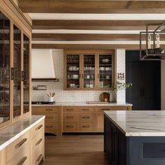 a large kitchen with wooden cabinets and marble counter tops, along with an island in the middle