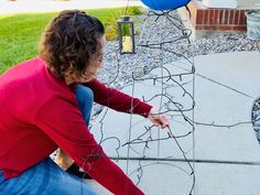 a woman sitting in front of a wire sculpture